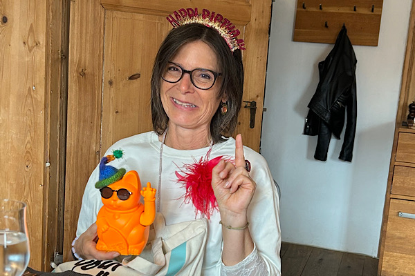 Claudia mit der orangefarbenen winkenden Katze mit Sonnenbrille.