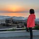 Anita Griebl steht seitlich am Strand im warmen Licht des Sonnenaufgangs und blickt ruhig in die Ferne – Symbol für Orientierung, Klarheit und inneren Weg.