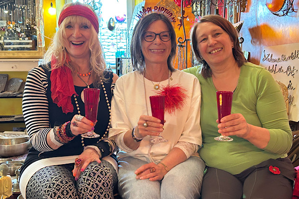 Gabi Oberberger, Claudia und ich stoßen im Feng‑Shui‑Laden mit roten Gläsern an.