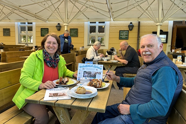 Anita und Karl sitzen im Biergarten des Tegernseer Bräustüberls vor ihrem Mittagessen.