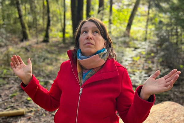 Wendepunkt Selbstständigkeit 2016. Anita Griebl steht im Wald in roter Jacke, die Arme geöffnet und den Blick nach oben gerichtet – ein Moment von Klarheit, Vertrauen und innerer Öffnung.