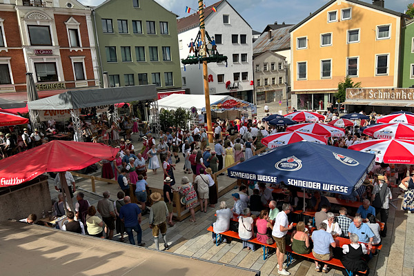 Blick auf die Bühne am Stadtplatz in Regen, wo Musiker spielen und Menschen in der Platzmitte einen Volkstanz aufführen.