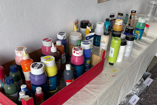 Acrylfarben, Pinsel und Malmaterialien liegen auf einem Tisch bereit – der kreative Auftakt zum Energie‑Mal‑Seminar im Garten