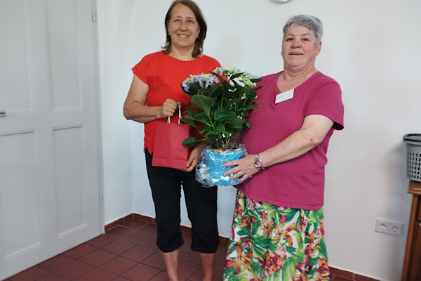 Margreth Kress überreicht mir nach meinem Vortrag in Straubing einen Hortensientopf und eine Geschenktasche.