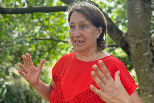 Anita Griebl steht seitlich in der Natur, Hände entspannt am Körper, sanftes Lächeln – Symbol für Erdung, Stabilität und innere Ruhe.