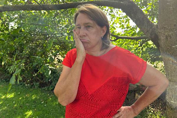 Anita Griebl hält eine Hand an die Wange, ein Lichtstrahl trifft ihr Gesicht – Moment der Innenschau und energetischen Verarbeitung.
