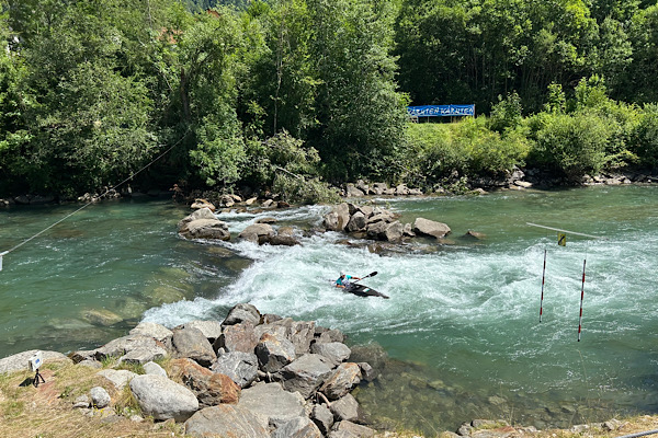 Ein Kanufahrer überquert eine strudelnde Stelle in einem gestauten Fluss – ein Bild für Blockaden und den Mut, Energie wieder in Bewegung zu bringen.