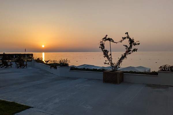 Goldener Sonnenaufgang am Strand mit einem aus Zweigen geformten Herz als Symbol für Liebe, Hoffnung und Neuanfang.