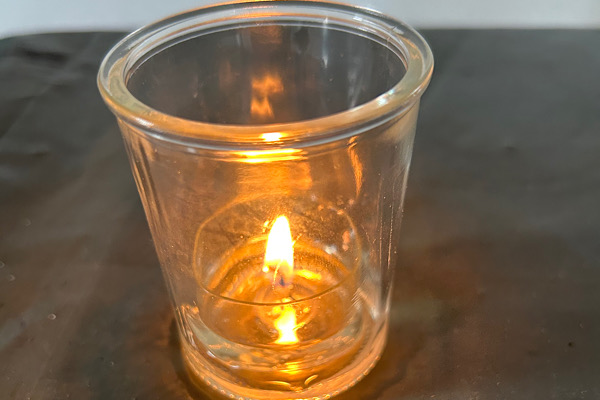 Eine kleine Kerze in einem Glas leuchtet sanft – ein Symbol für zarte Lebensenergie und behutsame innere Heilung.