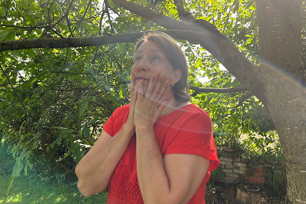 „Anita Griebl mit Lichtstrahl im Gesicht, Hand an der Wange, Blick nach oben – Moment der Herzöffnung und inneren Transformation.