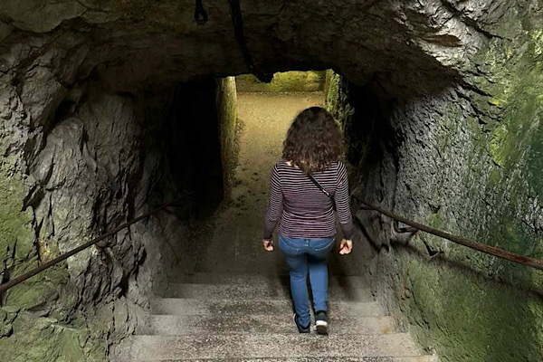 Frau geht eine dunkle Kellertreppe hinunter – Symbol für die energetische Bedeutung von Trotz und das Hinabsteigen in alte Ohnmacht