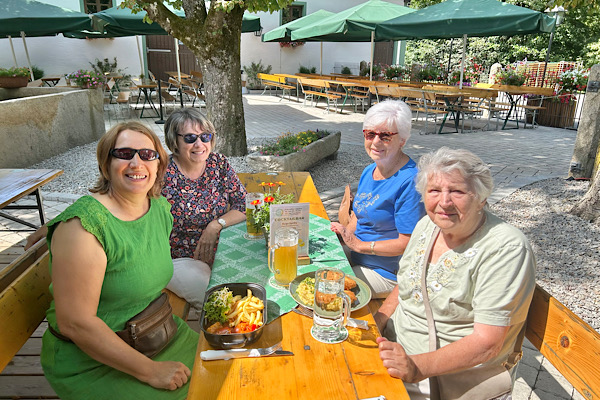 Vier Frauen sitzen gemeinsam im Biergarten des Lindner Bräu in Bad Kötzting vor dem Essen, lächelnd und in entspannter Atmosphäre.