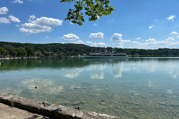 Schiff auf einem ruhigen See mit Landschaft und Wolken im Hintergrund – Symbol für innere Stabilität und Zuversicht.