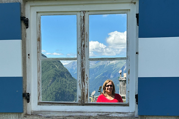 Anita Griebl spiegelt sich in einem Sprossenfenster und symbolisiert die Verbindung zwischen innerer und äußerer Welt.