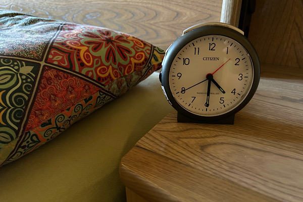 Wecker zeigt 4:30 Uhr neben einem Kopfkissen als Symbol für Leben gegen die innere Uhr und dauerhafte Erschöpfung.