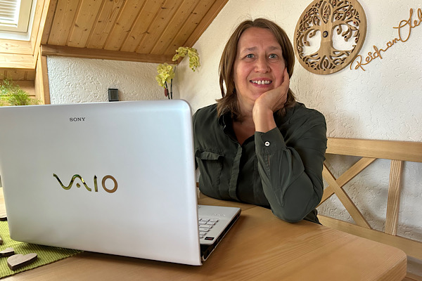 Anita Griebl sitzt am Laptop und blickt nach oben – ein Moment von Fokus, Lernen und dem Schritt ins Tun.
