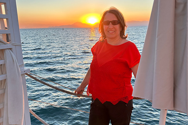 Anita Griebl steht kraftvoll auf einem Steg am Strand, hinter ihr die untergehende Sonne – ein Moment von Klarheit, Intuition und innerer Ausrichtung.