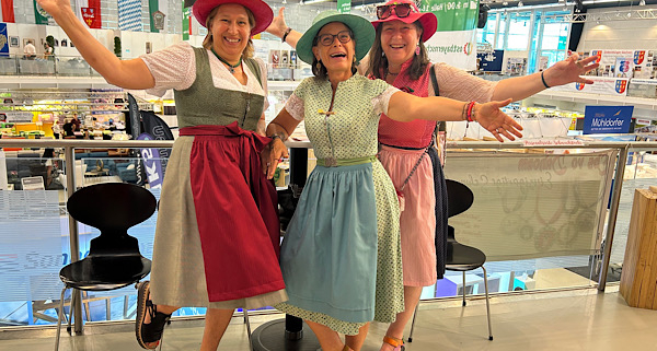 Gruppenfoto von Heidi, Claudia und Anita im Dirndl mit farbigen Hüten und ausgestreckten Armen.