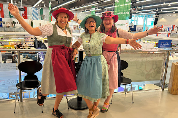 Gruppenfoto von Heidi, Claudia und Anita im Dirndl mit farbigen Hüten und ausgestreckten Armen.