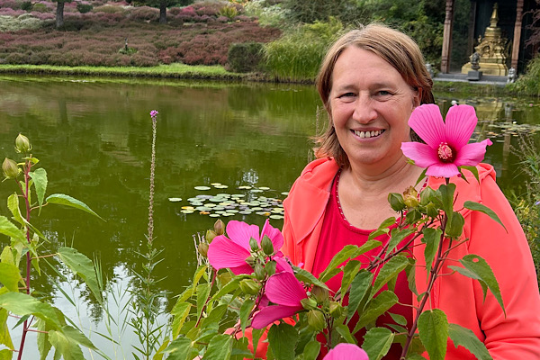 Anita Griebl zwischen Blumen in einem Park als Symbol für Selbstliebe, innere Heilung und persönliches Wachstum.