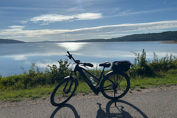 Fahrrad im Sonnenlicht am Ufer des Brombachsees; im Hintergrund liegt der See im warmen Licht.