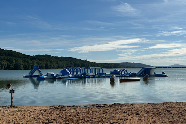 Aufblasbares Wasserspielgerät im Brombachsee, umgeben von Wasser und Grünflächen.