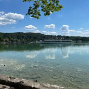 Ruhiger See mit weiter Landschaft im Hintergrund, ein stiller Moment, der Leichtigkeit und innere Weite symbolisiert.