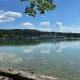 Ruhiger See mit weiter Landschaft im Hintergrund, ein stiller Moment, der Leichtigkeit und innere Weite symbolisiert.