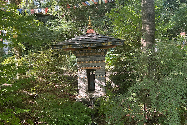 Nepalesisches Häuschen im Nepalpark, umgeben von Grün und Bäumen.