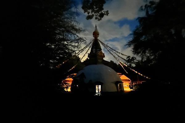 Nepaltempel im Abendlicht; im Inneren leuchtet ein einzelnes Licht, der Rest des Bildes liegt in dunkler Umgebung.