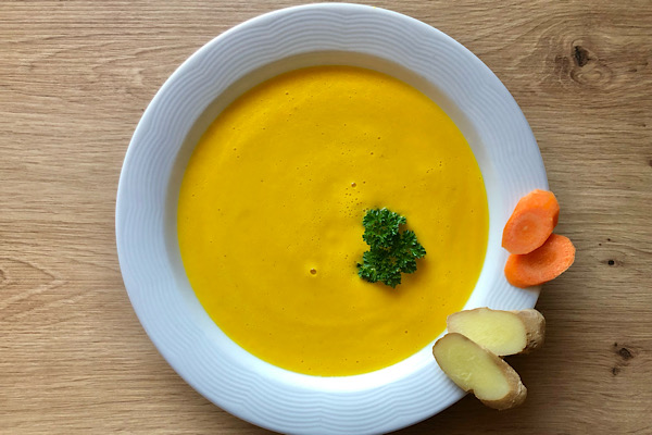 Teller mit Karottensuppe und Karottenscheiben am Rand – leichte, pflanzliche Mahlzeit für meine Detox‑Praxis.